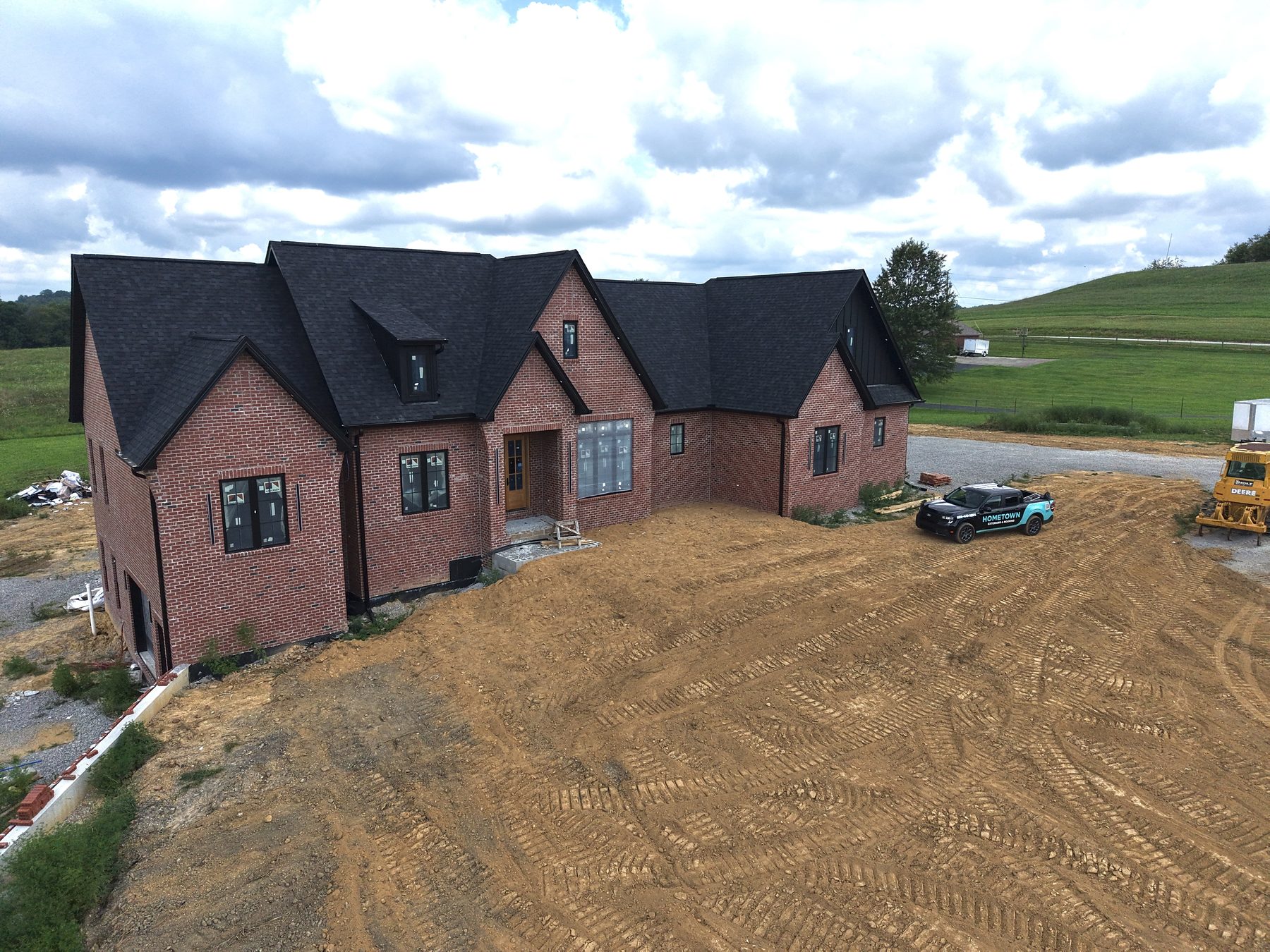 Brick home with 6-inch black gutters, aluminum board-and-batten siding, black soffit and metal wrapping by Hometown Exteriors and Roofing